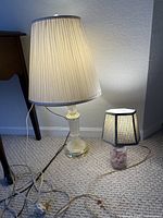 Large clear glass column lamp with pleated shade beside small jar-base lamp with plaid shade