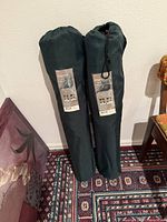 Two dark green carry bags standing upright showing product labels