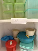 Stacked green plastic square tubs on upper shelf, turquoise rectangular tubs, cream round containers and blue round bowl below