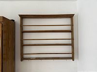 Front view of wall-mounted wooden shelf with four rails and hooks