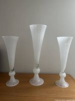 Front view of three white glass trumpet vases