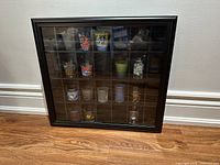 Front view of black display case showing glass door and grid compartments