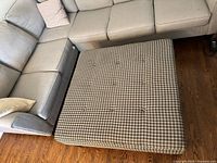 Top view of square ottoman beside sectional sofa showing houndstooth pattern and button tufting
