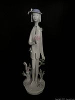 Front view of male figurine holding pink heart, floral base details visible