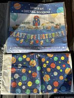 Front of banner kit package and folded space-theme tablecloth