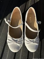 Top view of both shoes showing bow detail, patent finish, interior branding