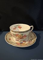 Teacup on saucer showing floral pattern and gilt border