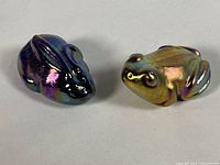 Both iridescent glass frog paperweights side by side