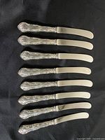 All eight Birks butter spreaders lined up showing handles and blades