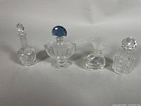 All four vintage clear glass perfume bottles displayed together