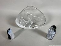 Front view of crystal swan paperweight flanked by two penguin figurines