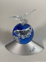 Front view showing clear bird atop blue crystal globe with silver continents, base signed