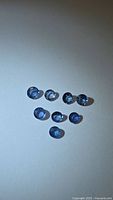 Eight round blue sapphires arranged on light background