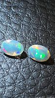 Pair of oval faceted opals on black textured background