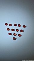 Triangular arrangement of small red round gemstones on neutral background