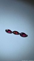 Three oval hot pink sapphires on white background