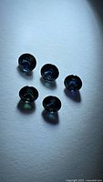 Five round faceted deep blue sapphires on white background