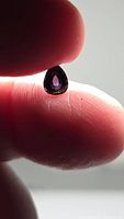 Pear cut deep purple spinel held between fingers