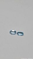 pair of oval sky blue topaz gemstones on neutral background