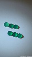Eight round green cabochons grouped on white background