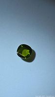 Top view of vivid green cushion cabochon peridot