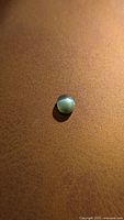 Round green cabochon Alexandrite displaying cat’s-eye under direct light