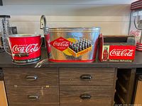 All three Coca-Cola tins side by side showing shapes and graphics