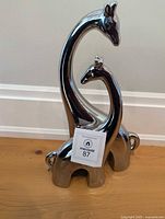 front view of polished metal mother and calf giraffe statue