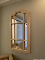 Front view of arched cream wooden frame mirror on wall