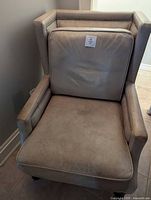 Front angled view of beige leather armchair showing cushion and nailhead trim