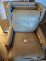 Front view of beige leather armchair, loose cushion in place