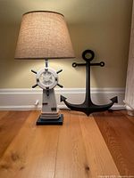 Lamp with shade and wall anchor displayed on wood floor against wall