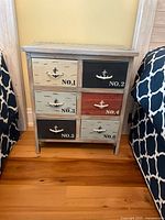 Front view of nightstand between beds showing six drawers with rope pulls and distressed finish