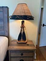 Full view of lamp on nightstand showing shade, oar base, rope detail