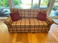 Front view of plaid sleeper sofa with two red pillows