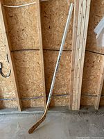 Full view of white Los Angeles Kings hockey stick leaning against wall