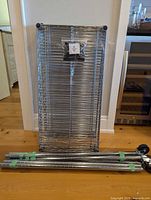 Stacked chrome wire shelves, four posts with green tape, hardware bag visible