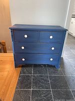 Front view of blue four-drawer dresser on slate floor