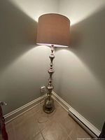 Full view of lamp standing in corner showing entire height, base, and shade