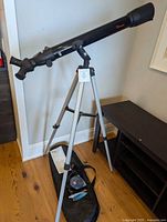 Telescope on tripod with bag and accessories on floor