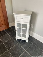 Front view of white cabinet showing drawer and glass door
