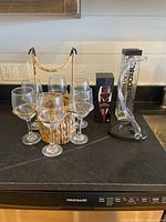 Group view showing six glasses in wicker caddy, acrylic bottle holder, Corkcicle package and Magic Decanter box