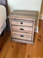 Front view showing entire wooden nightstand with three drawers and hardware