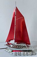 Front view showing chrome hull, red sails, overall form
