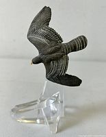 Side view of resin hawk figurine on clear faceted base