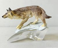 Left side profile of resin wolf atop clear glass base