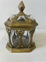 Front view of hexagonal brass-tone framed bubble glass apothecary jar with lid attached