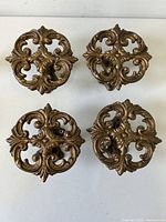 Top view of four cast-iron ornate rosette holdbacks