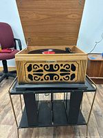 Record player lid open, front grille visible, vinyl on platter