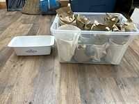 Plastic tote with wrapped clear glass tumblers beside CorningWare loaf dish